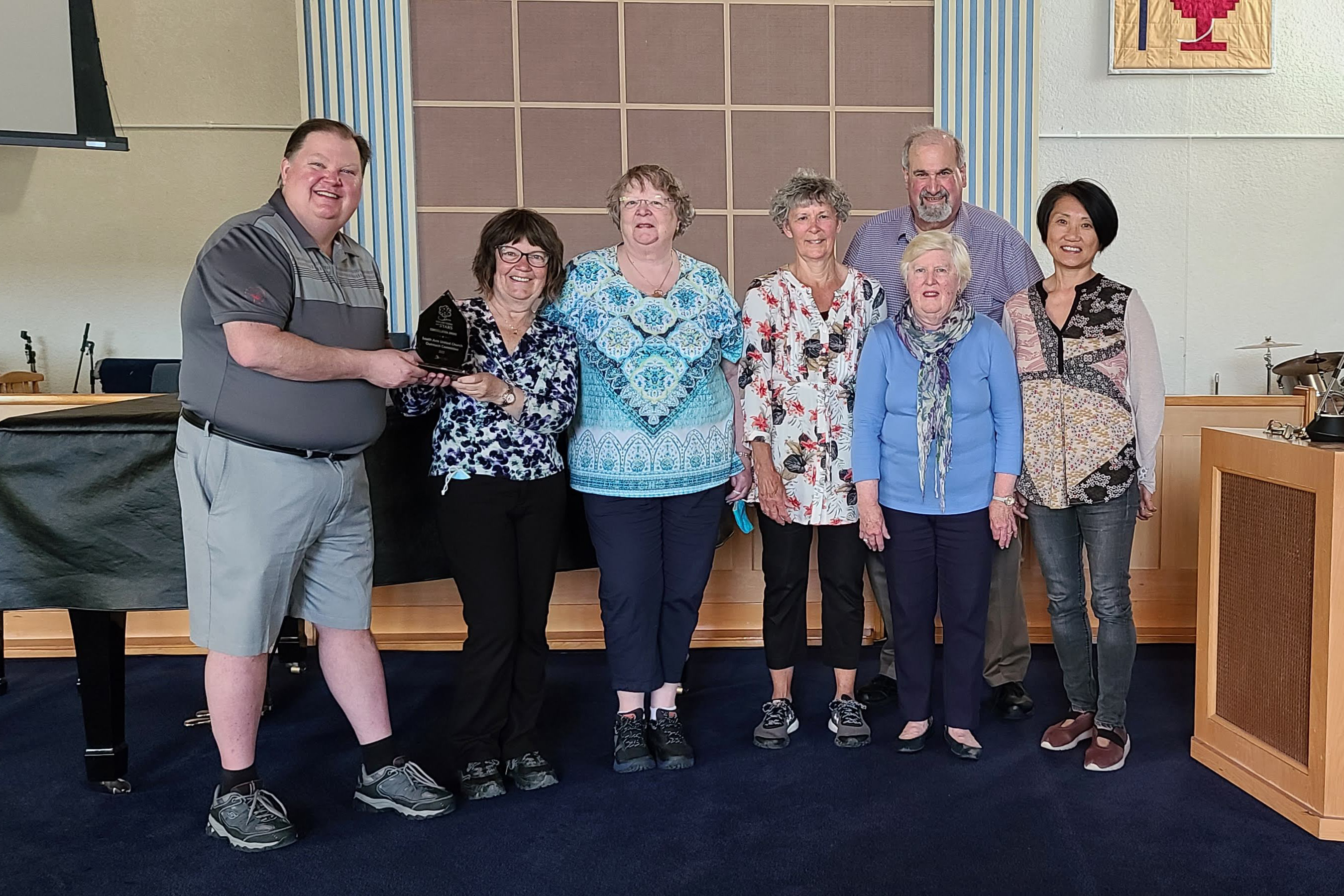 A group of people standing in a church, with two of them holding an award