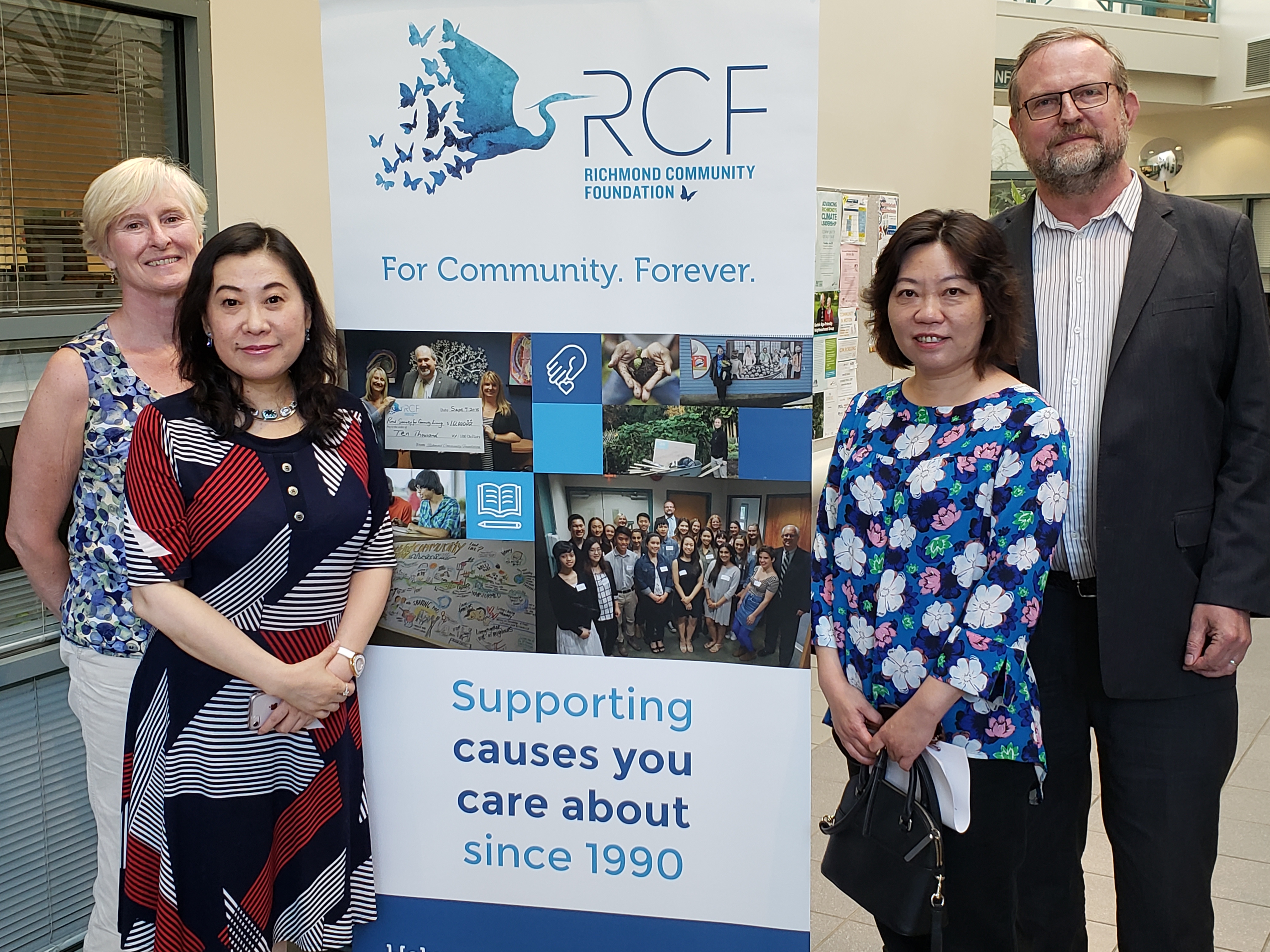 Three Women and One Man Standing Next to Richmond Community Foundation Banner