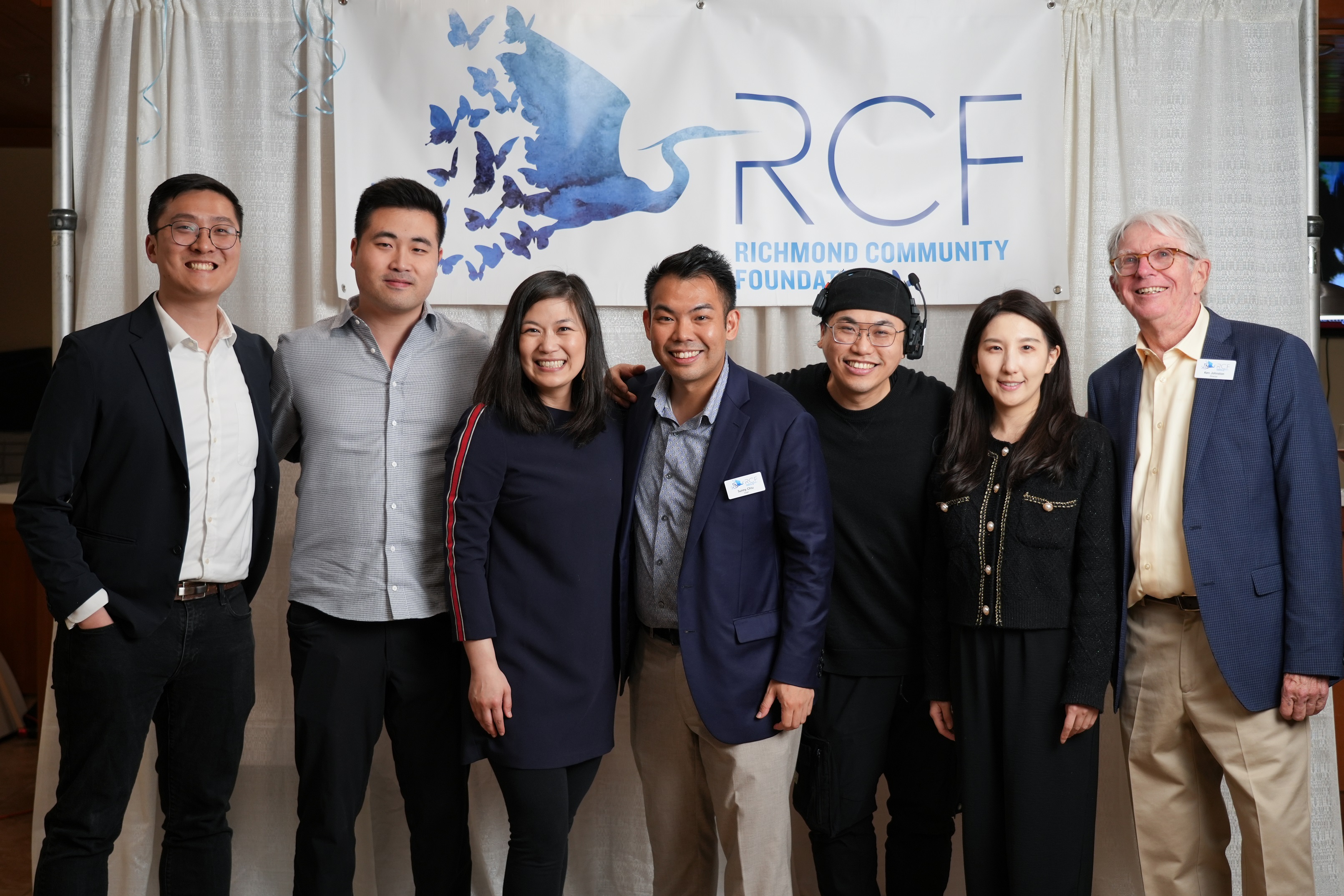 A group of people standing and smiling in front of the Richmond Community Foundation logo