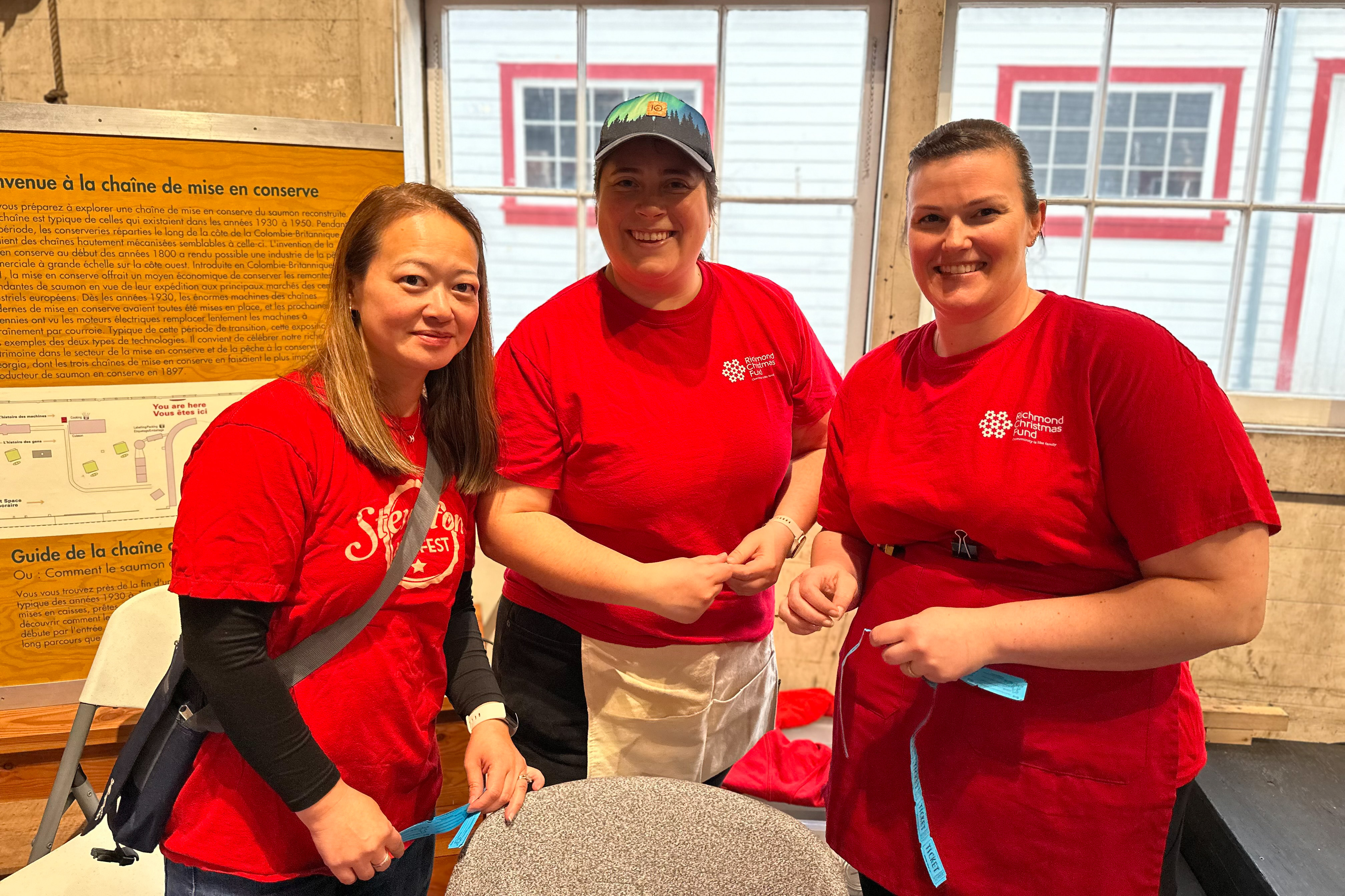 Three volunteers in red t-shirts holding raffle tickets