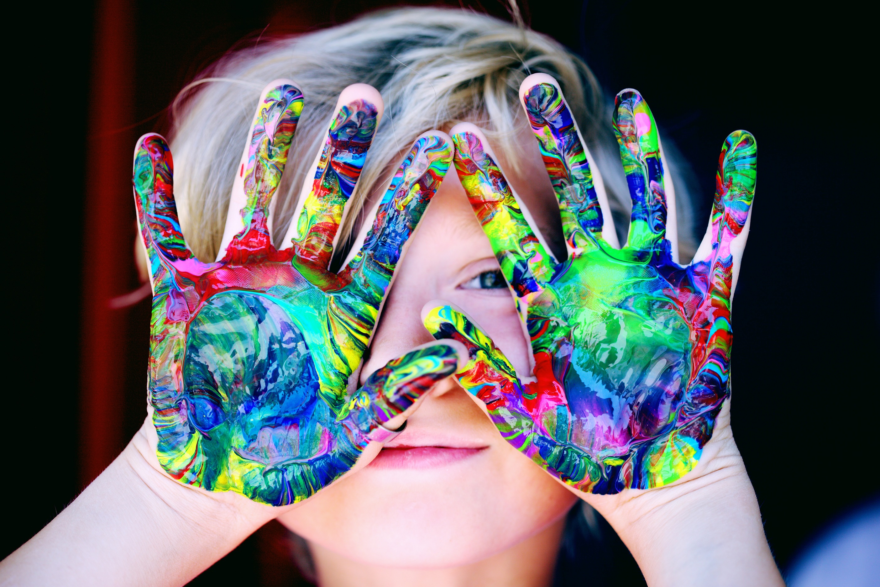Child Holding Paint-Filled Hands Up to Face