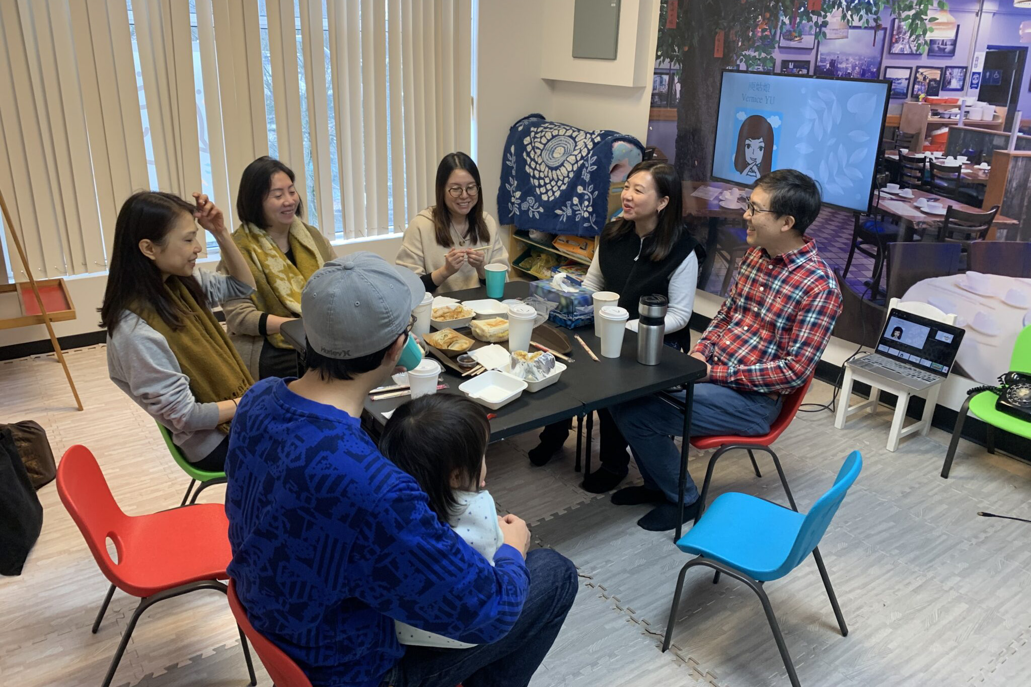 A group of people sitting around a table, smiling and laughing